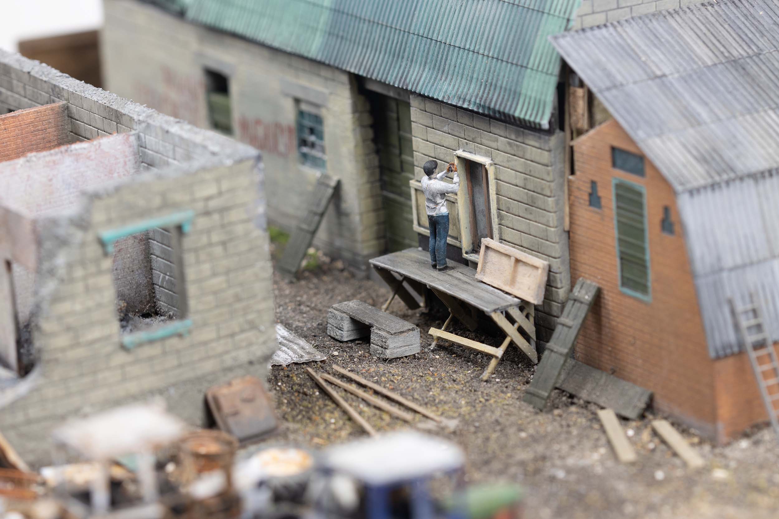 Model of man repairing a building with scrap ammunition crates in the village of Kamianka, Ukraine, by artist Thomas Doyle for the Howard G. Buffett Foundation