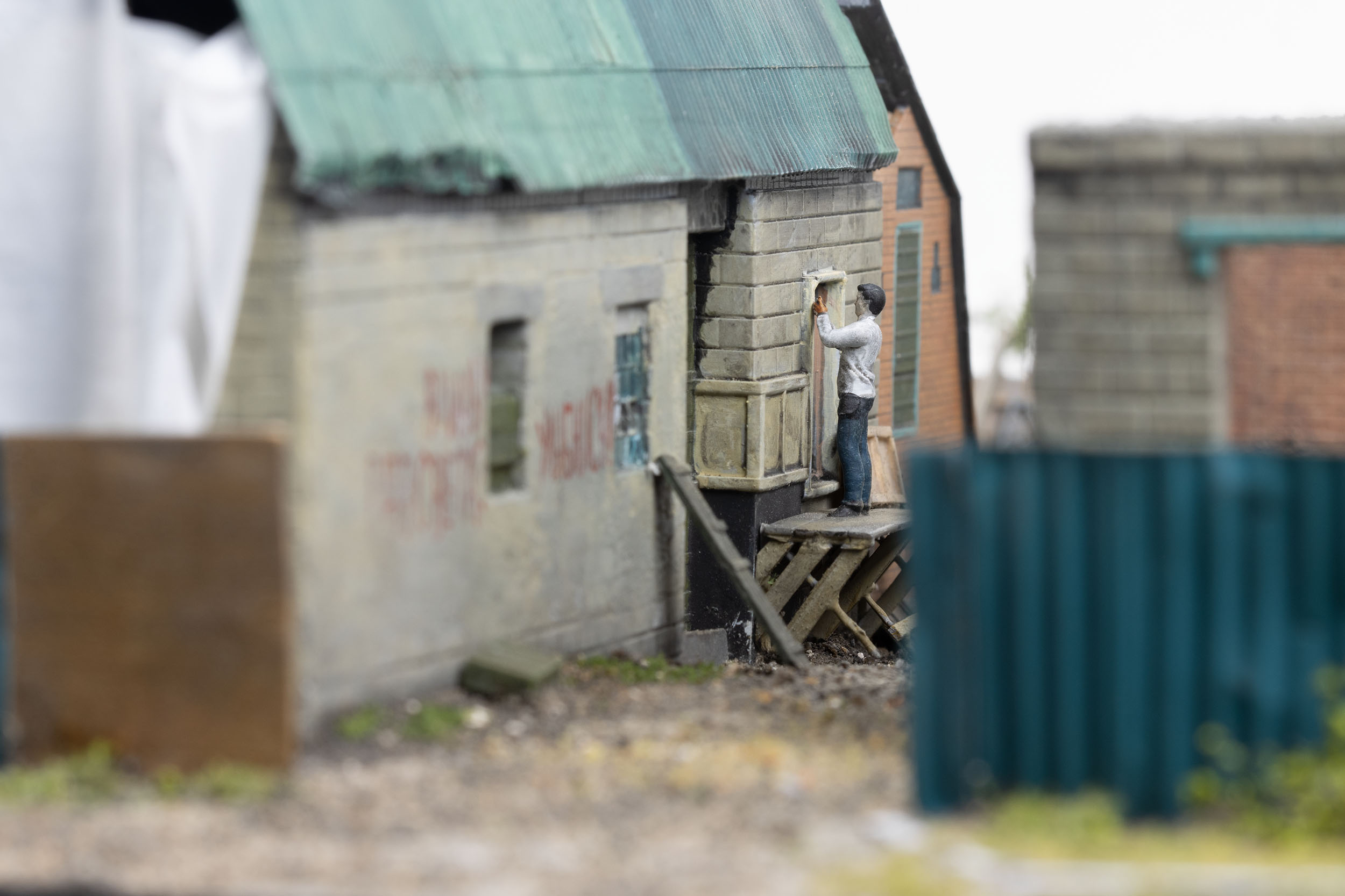 Model of man repairing a building with scrap ammunition crates in the village of Kamianka, Ukraine, by artist Thomas Doyle for the Howard G. Buffett Foundation
